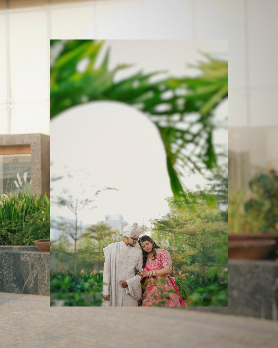 Couple in traditional outfits seen through a framed arch of palm leaves